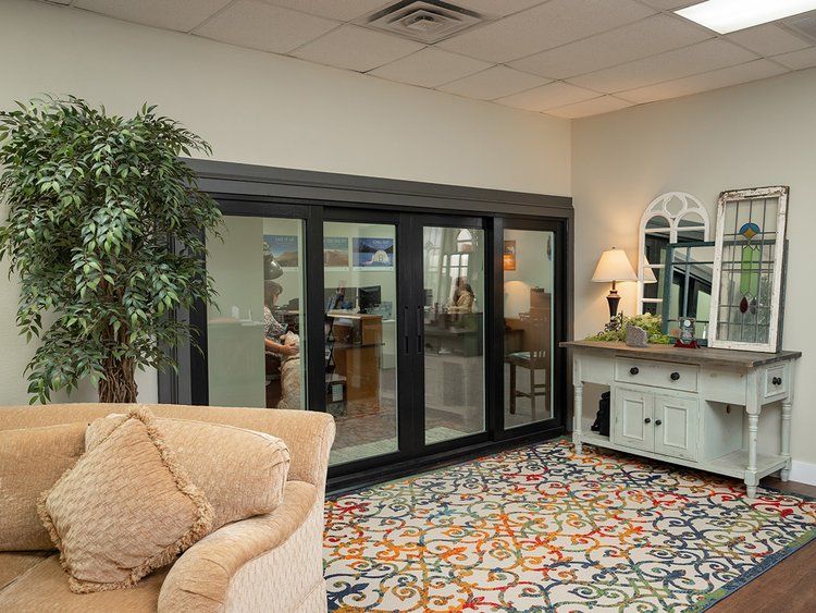 A living room with a couch , chair , table and sliding glass doors.