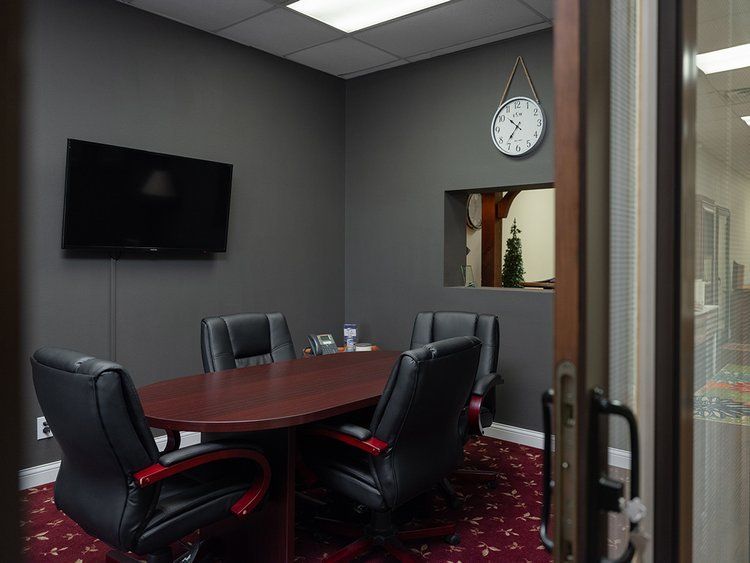 A conference room with a table and chairs and a clock on the wall.