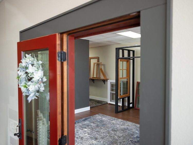 A red door is open to a room with a wreath on it.