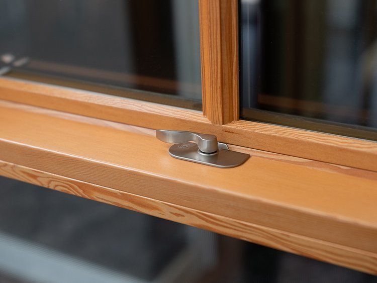 A close up of a wooden window with a stainless steel latch.