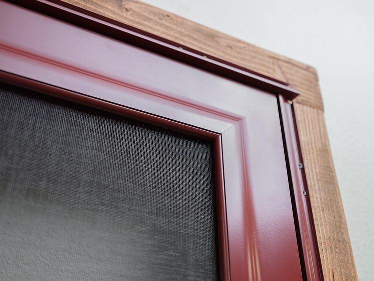 A red screen door with a wooden frame