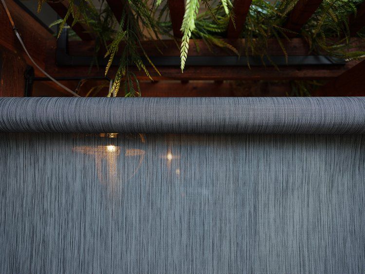 A close up of a gray carpet with a wooden fence in the background.