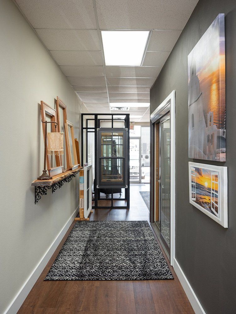 A hallway with a rug and paintings on the wall