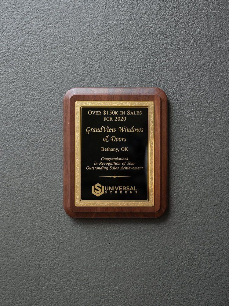 A wooden plaque with a gold border is hanging on a wall.