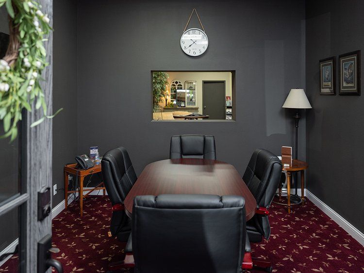 A conference room with a long table and chairs and a clock on the wall.
