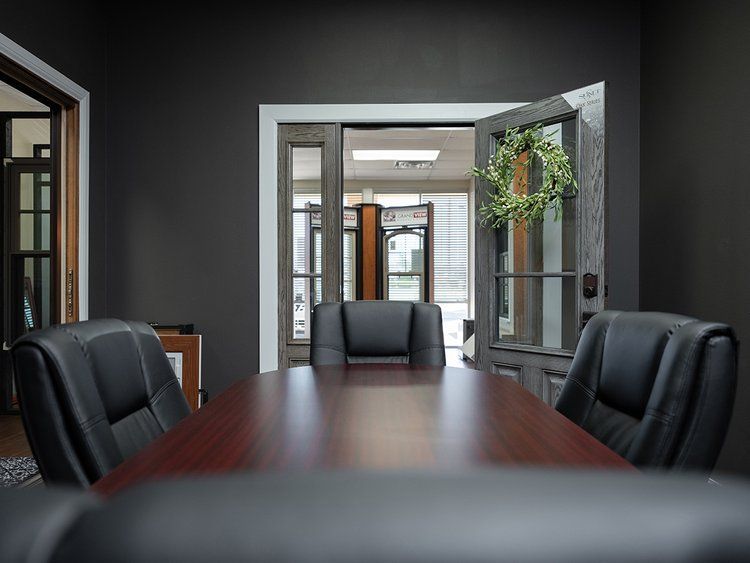 A conference room with a wooden table and black chairs.