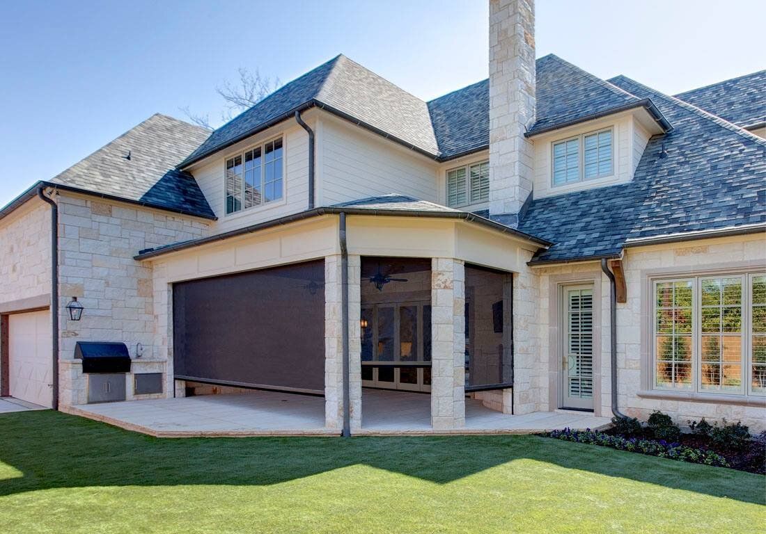 A large white house with a screened in porch and a large lawn in front of it.