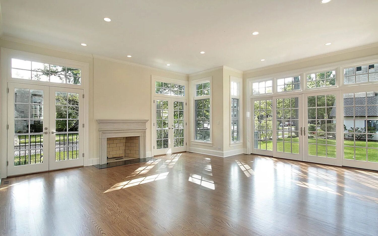 An empty living room with a fireplace and lots of windows.