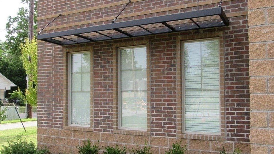 A brick building with three windows and a canopy over them
