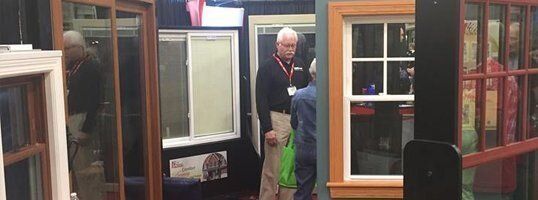 A group of people are standing in a room looking at windows.