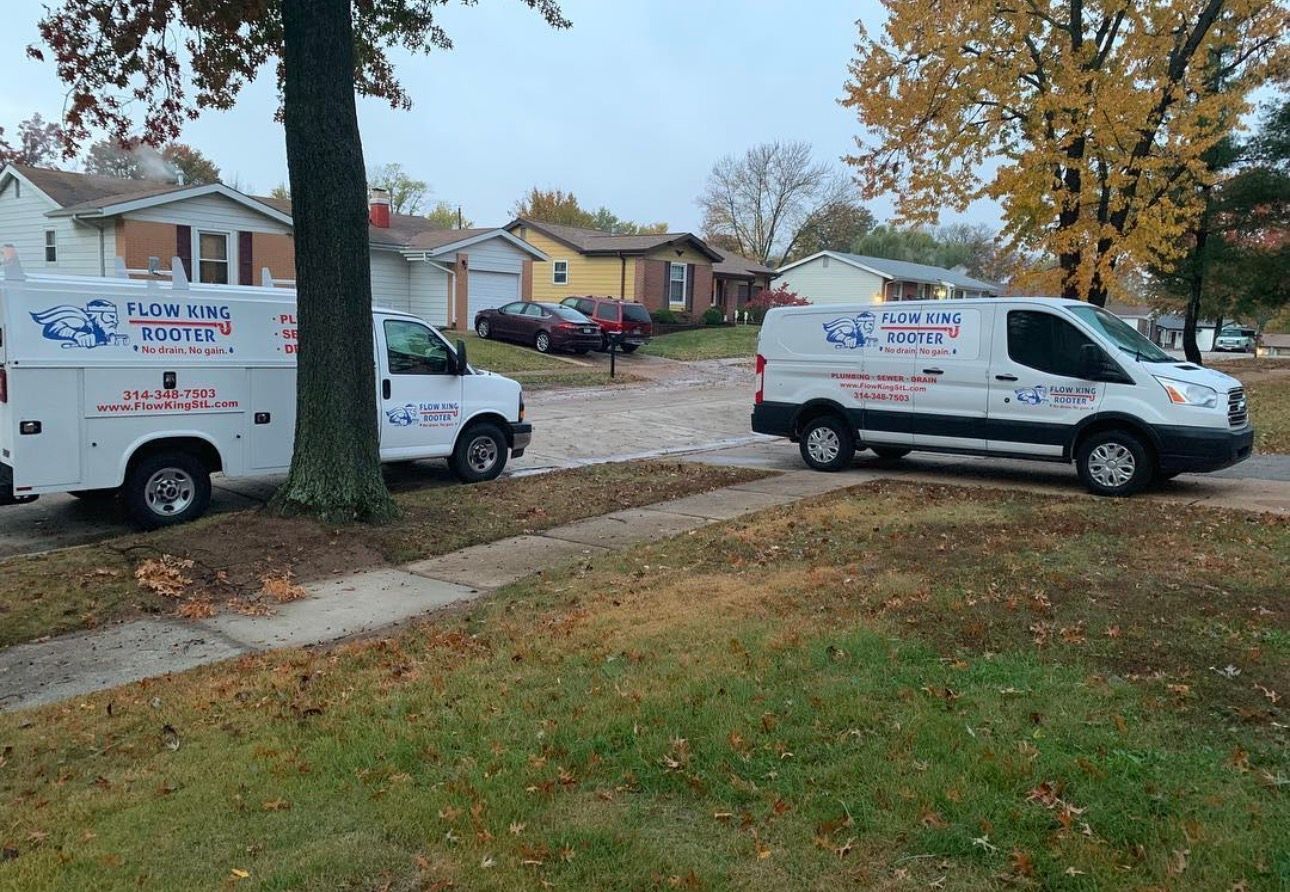 Two white service vans parked on a residential driveway, advertising 
