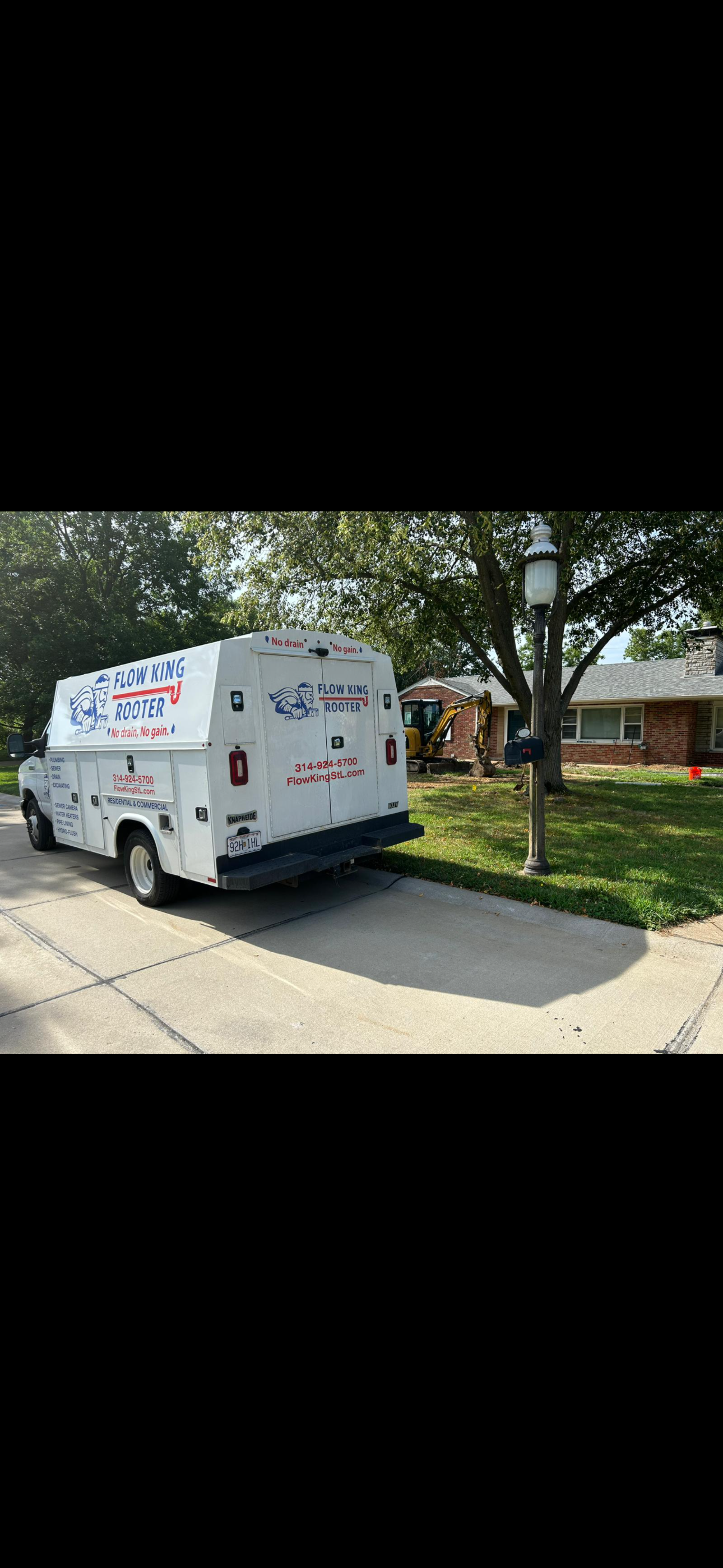 White service van parked in front of a house on a driveway, the van has text on it, residential neighborhood.
