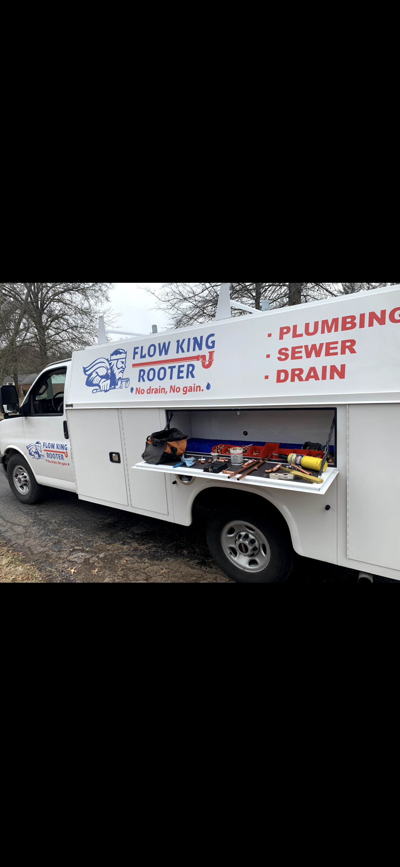 White plumbing service truck with open tool compartment.