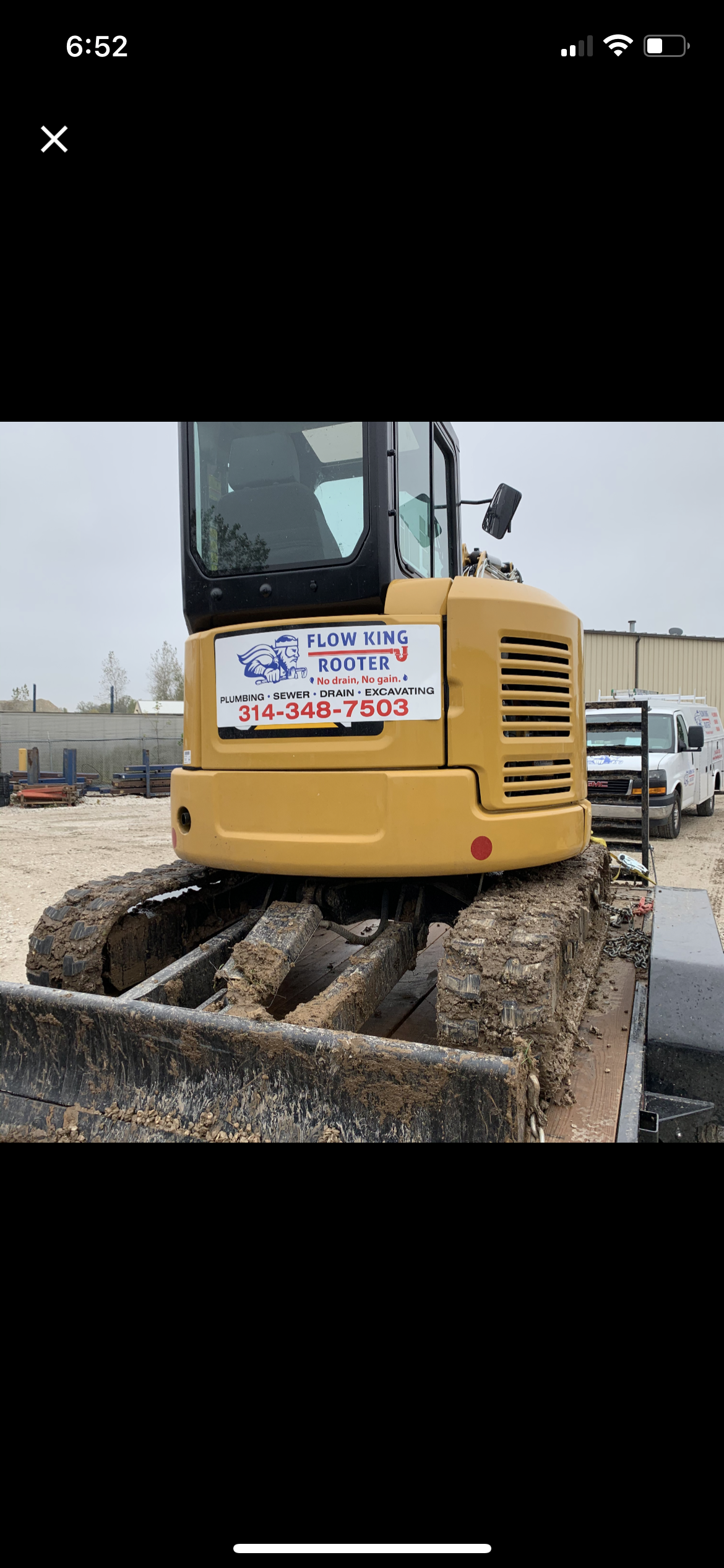 Yellow excavator on tracks, with a sign, outdoors on a construction site.