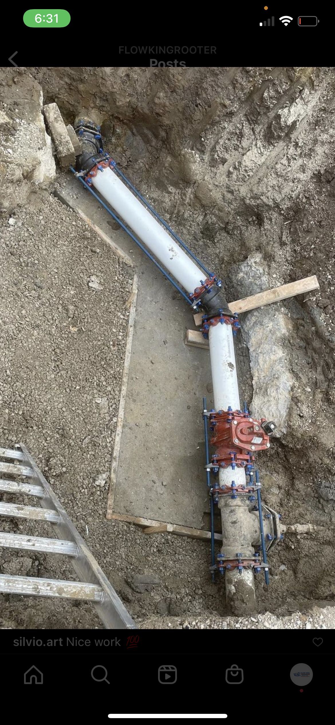 Pipes and valve installation in an excavated trench. A ladder is in the foreground.