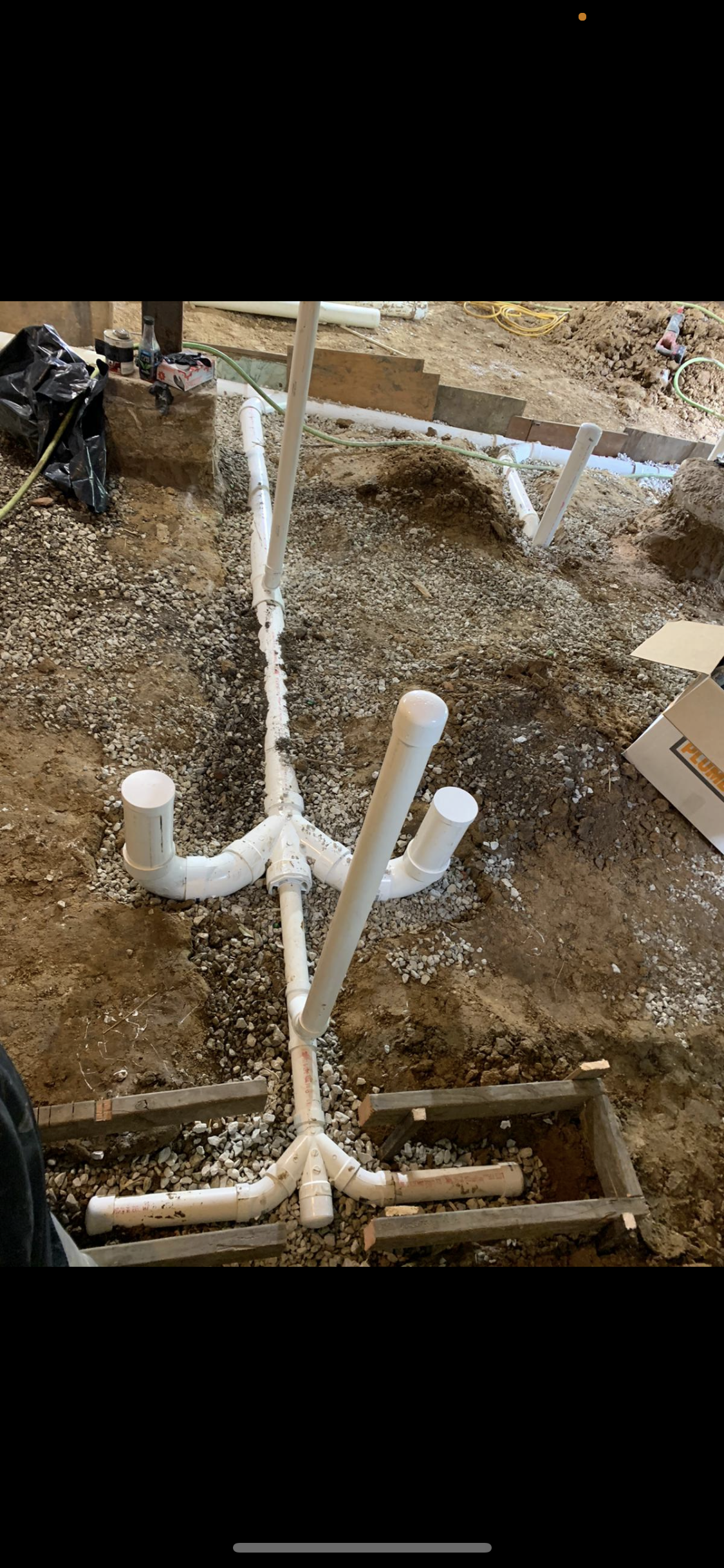 PVC plumbing system installed in a dirt and gravel setting, showing pipes and fittings.