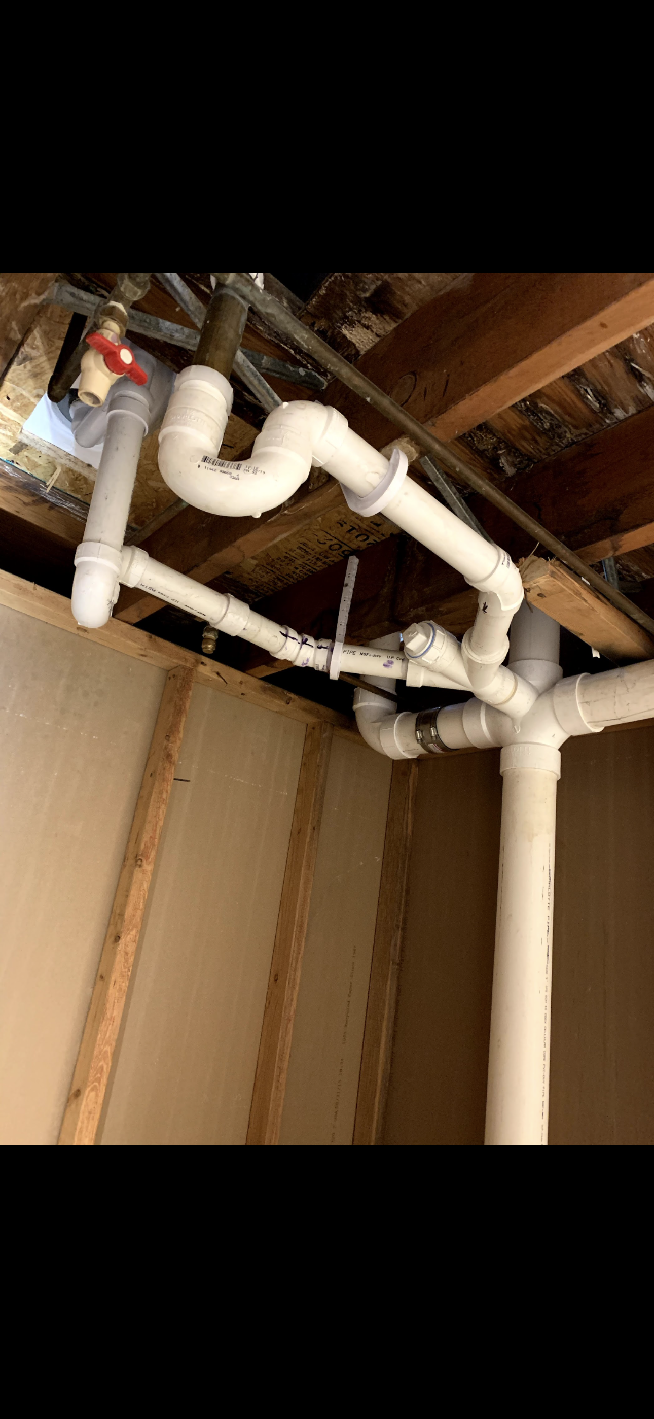 White PVC pipes installed under a wood ceiling.