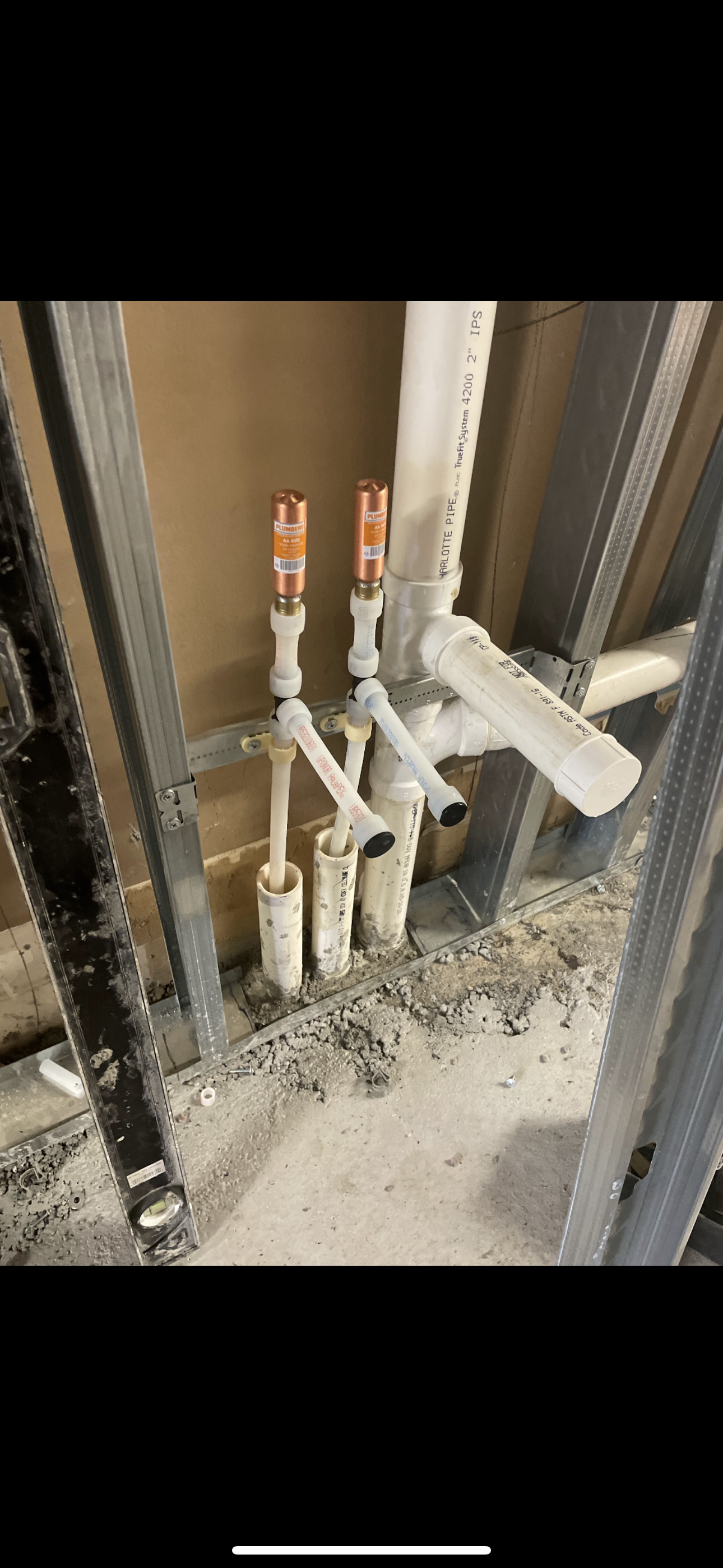 Plumbing pipes and copper fixtures installed in a wall frame.