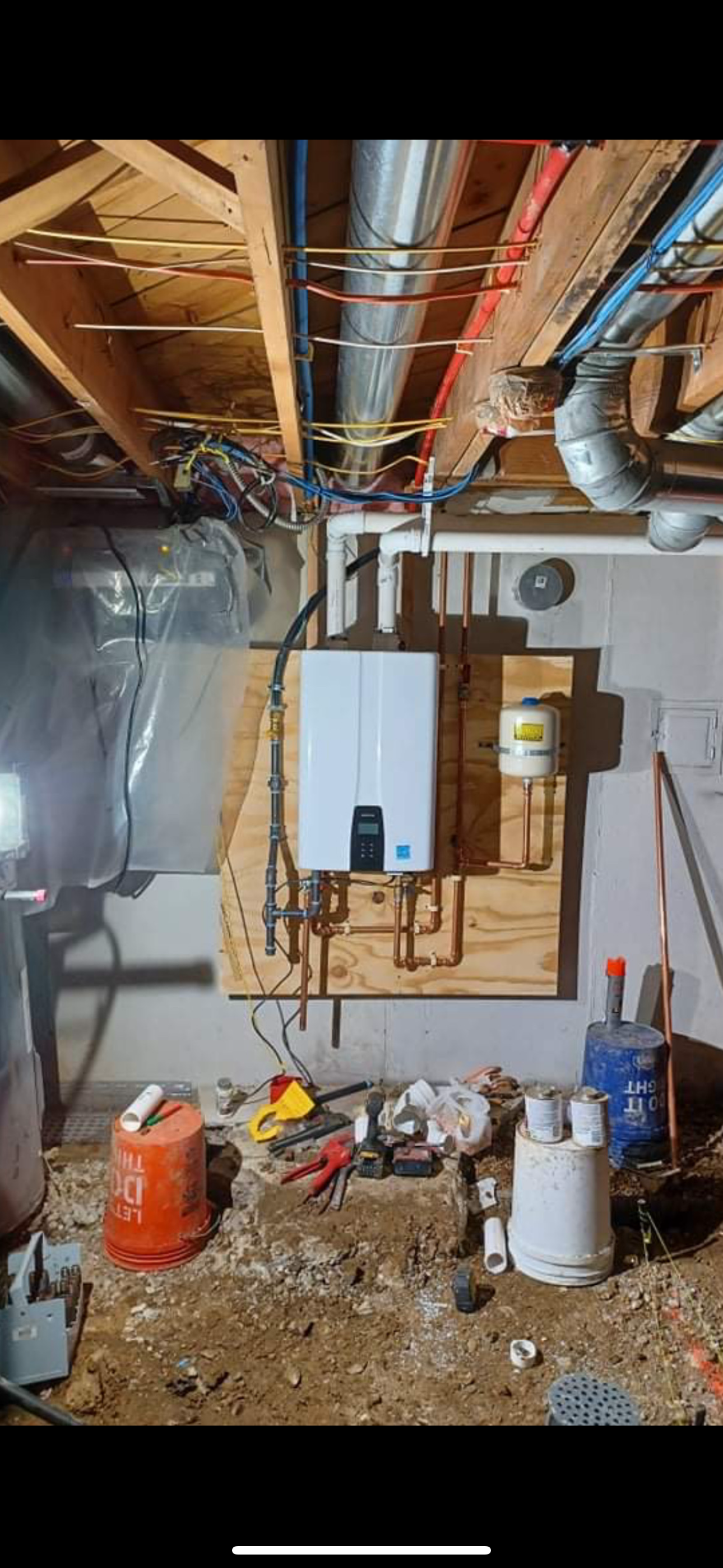 A basement with exposed pipes, a water heater, and debris on the floor.
