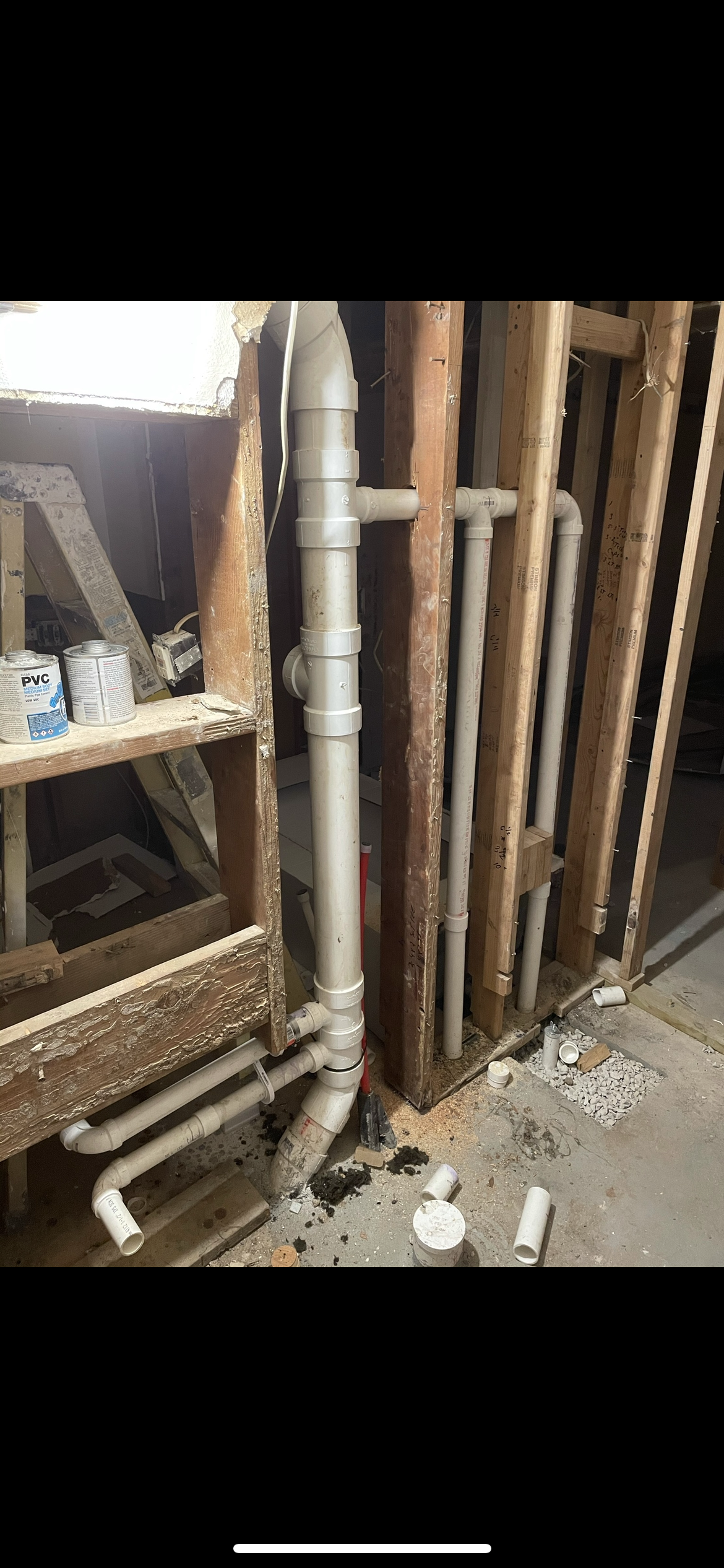 Plumbing pipes installed in a wooden wall framework, in a construction setting.