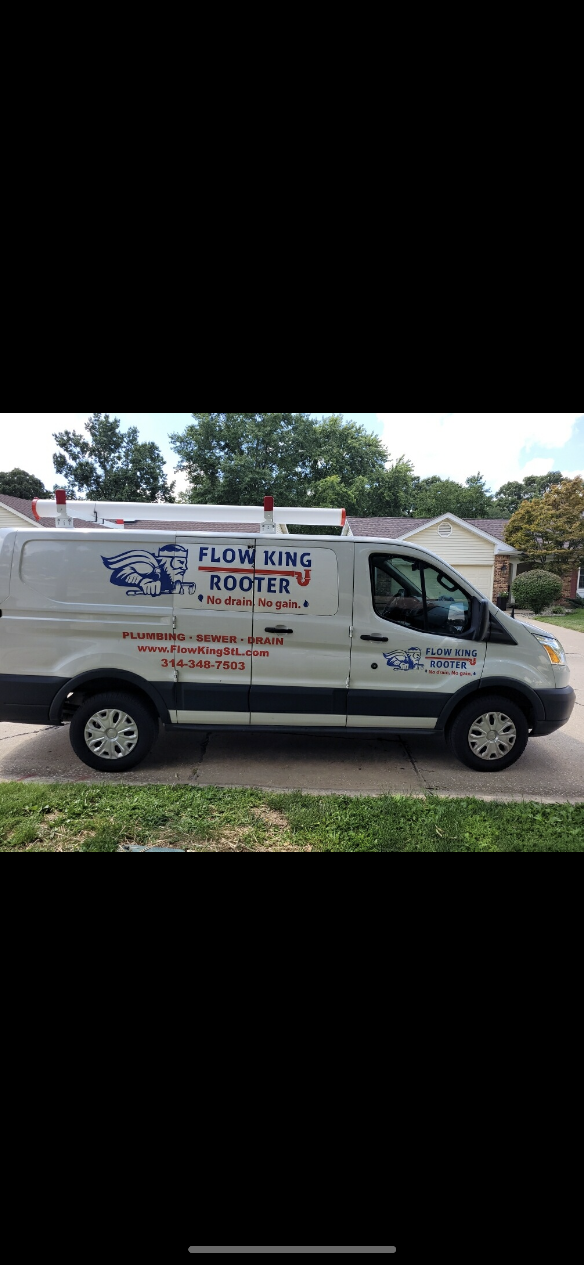 White plumbing service van parked on a paved driveway in front of a house.
