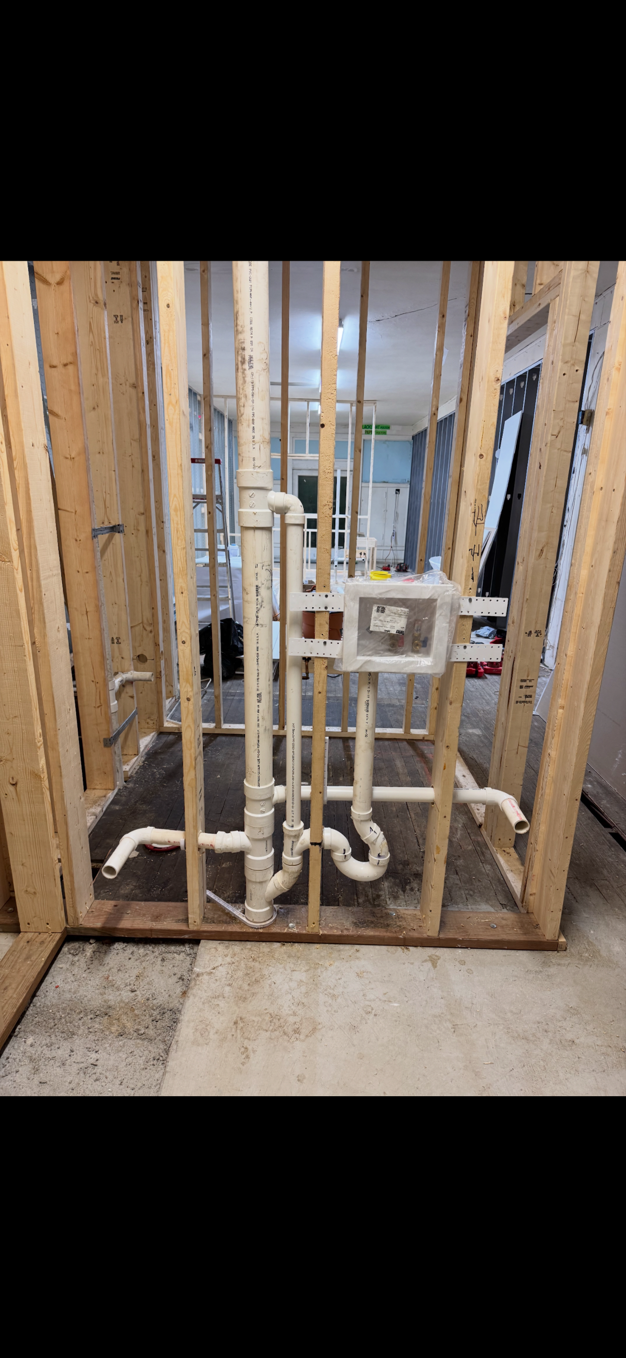 Framed wooden construction with installed white PVC pipes in what appears to be a bathroom renovation.