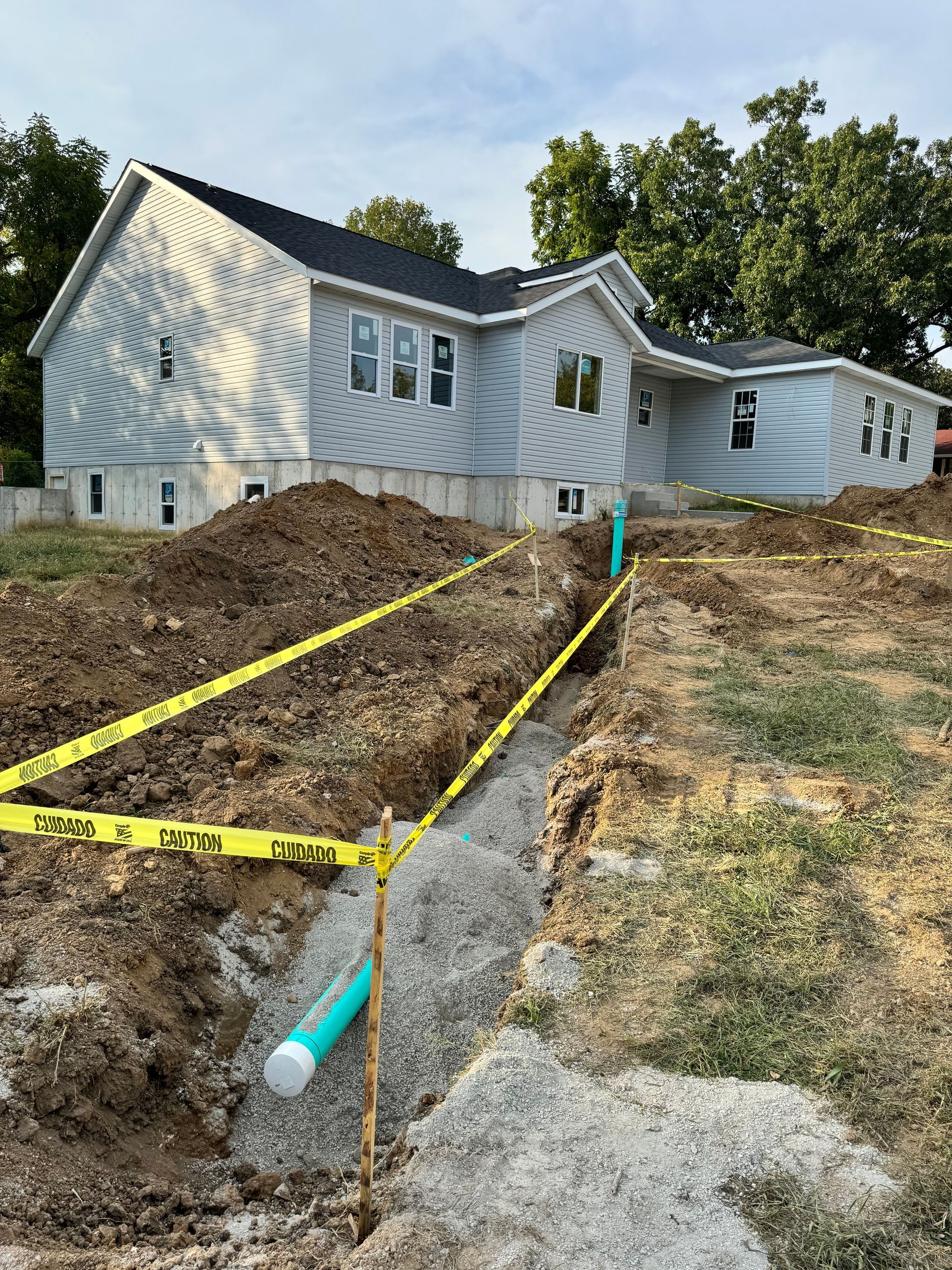 House under construction with trench and caution tape.