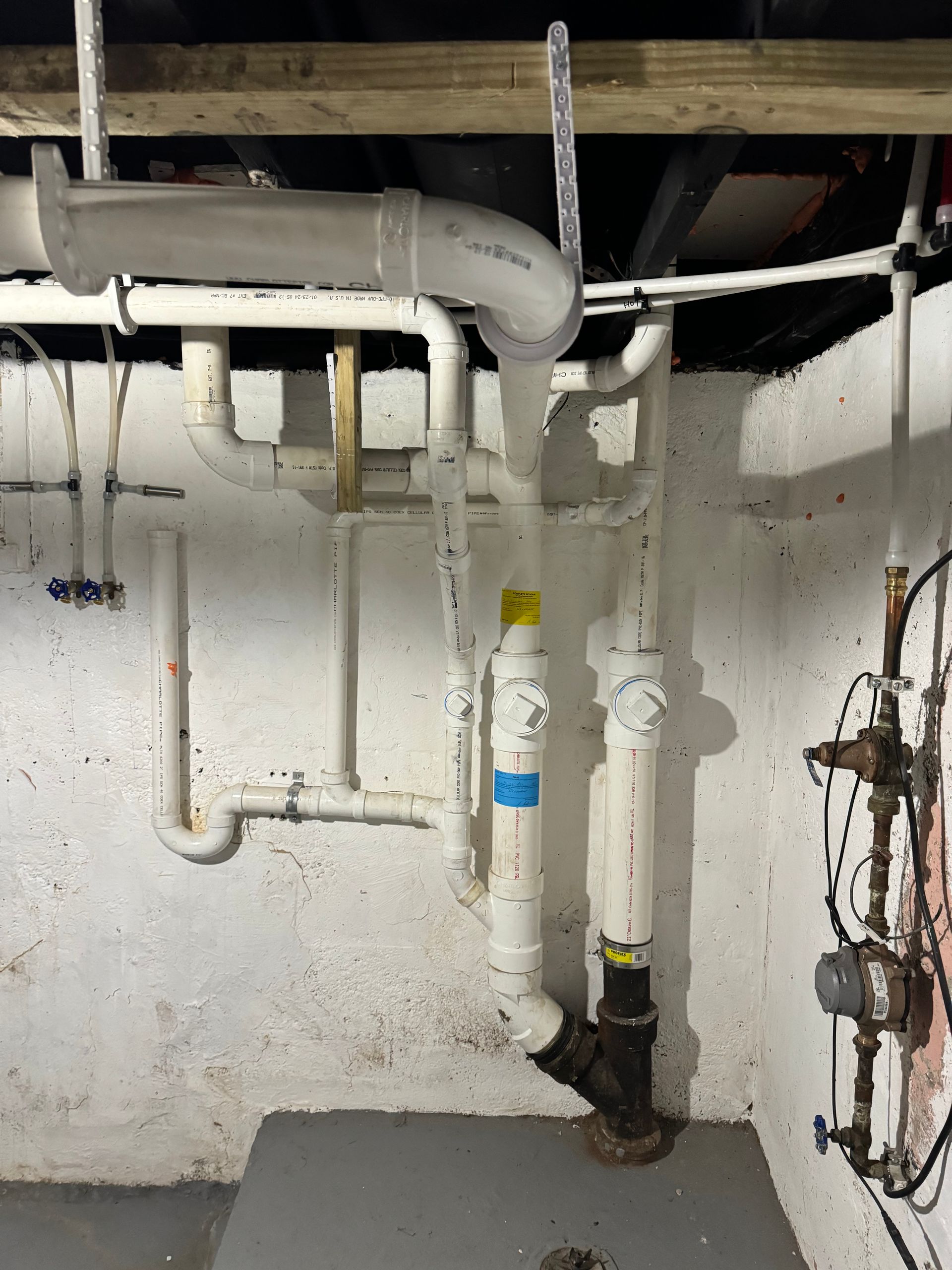 White pipes and plumbing against a white and gray concrete wall.