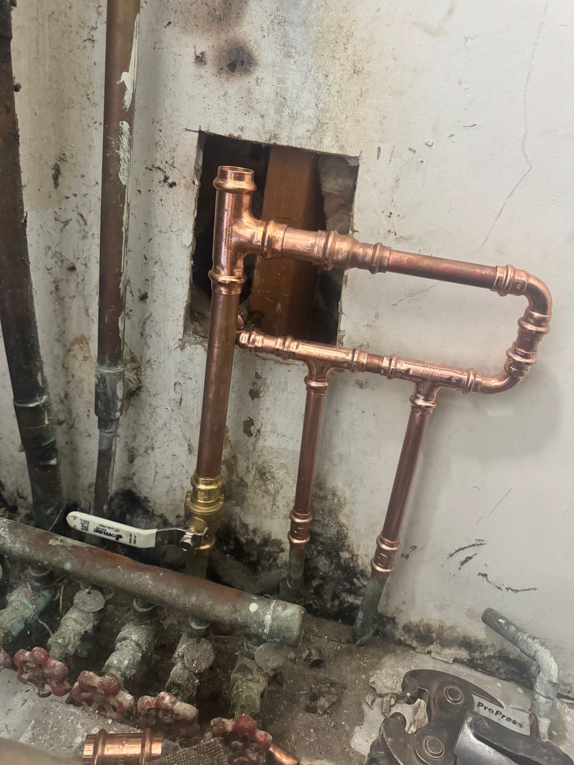 Copper pipes installed on a wall, connected and ready for water flow.