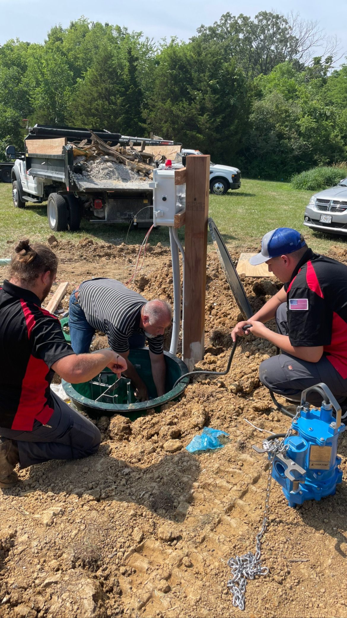 Three workers installing equipment outdoors near a utility pole and truck.