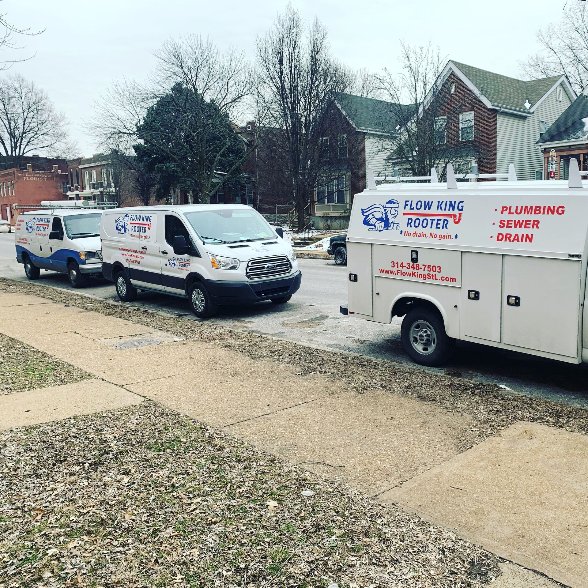 Three plumbing service vans parked on a residential street.