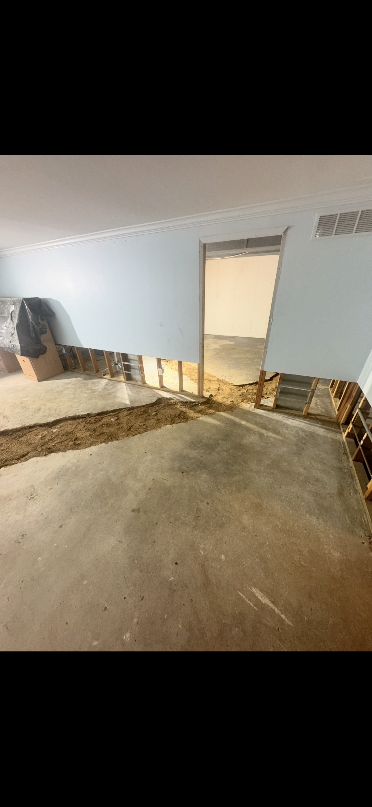 A room with water damage; the flooring and wall is ripped up.