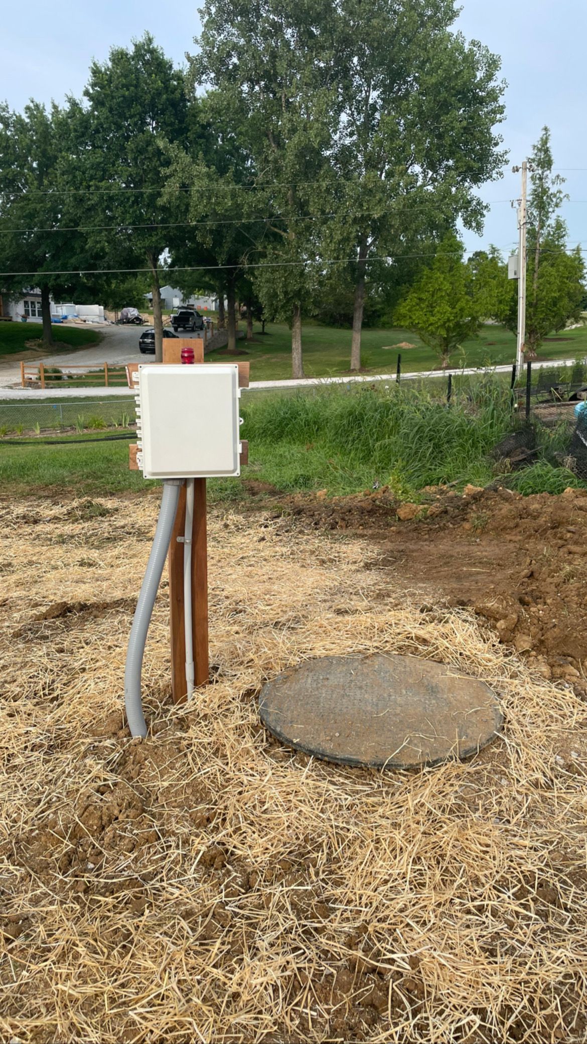 Outdoor electrical box and concrete cover in a construction area, surrounded by wood chips.