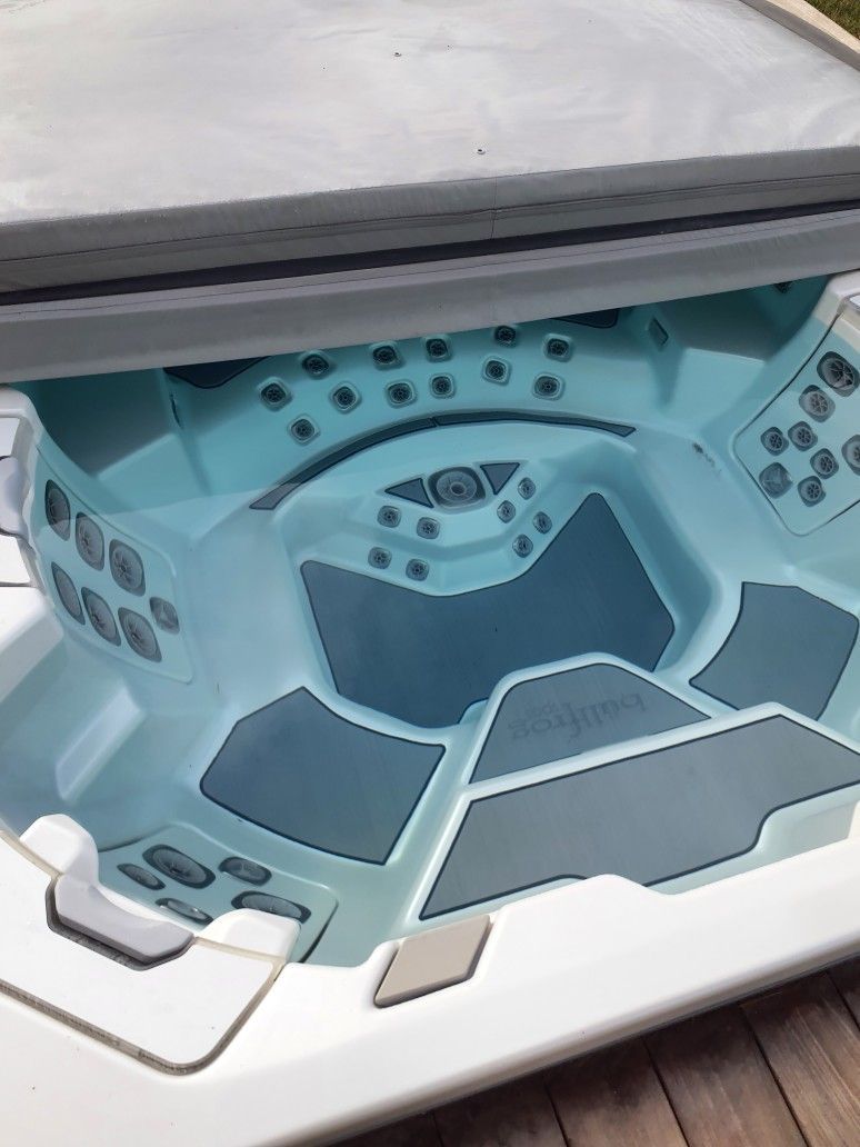 A blue and white hot tub is sitting on a wooden deck.