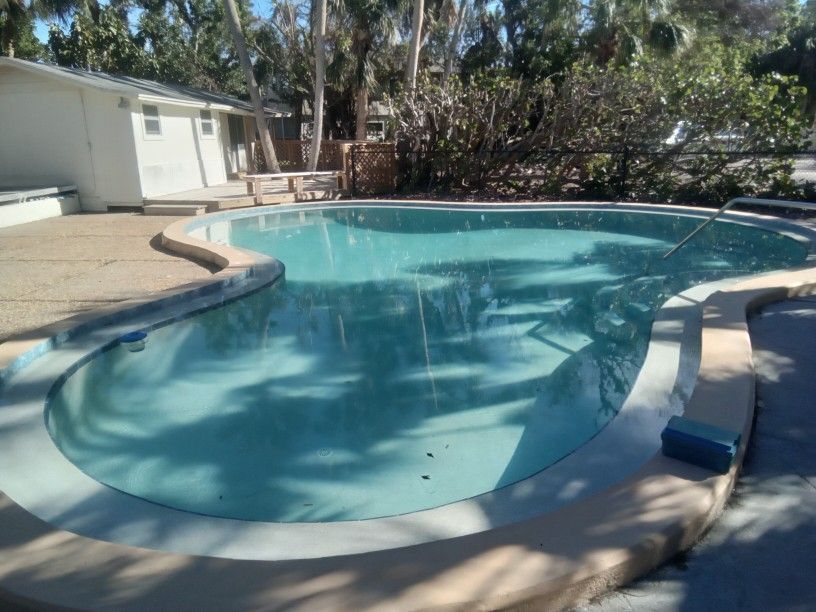 A large swimming pool with a house in the background.