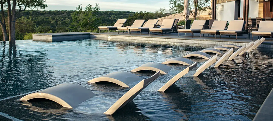 A row of lounge chairs are sitting next to a swimming pool.