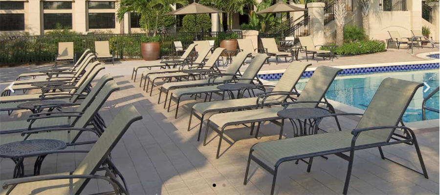 A row of lounge chairs next to a swimming pool.