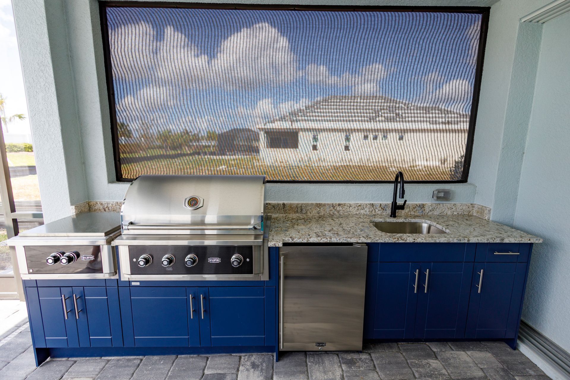 A kitchen with blue cabinets, a grill and a sink