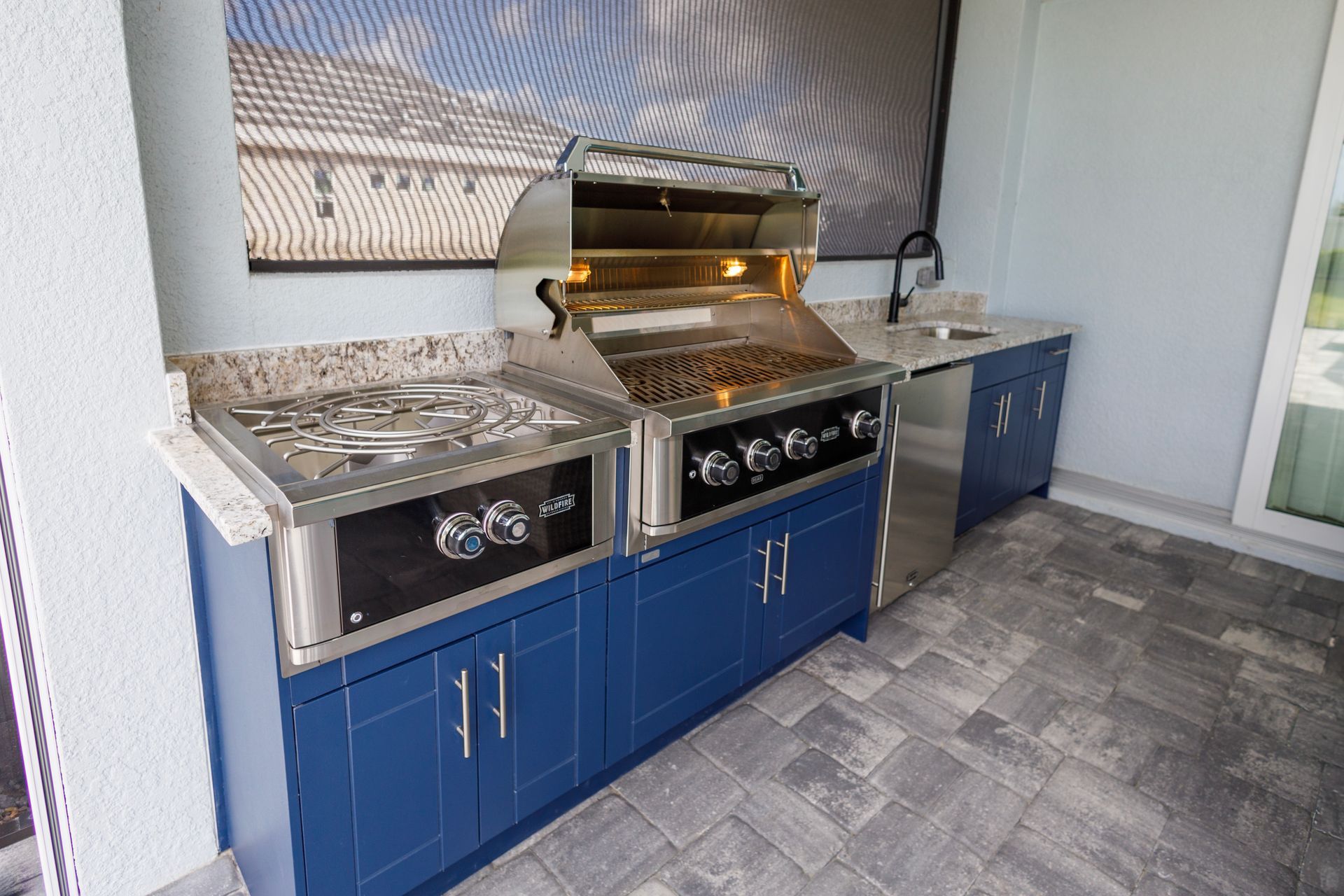 An outdoor kitchen with blue cabinets and a grill