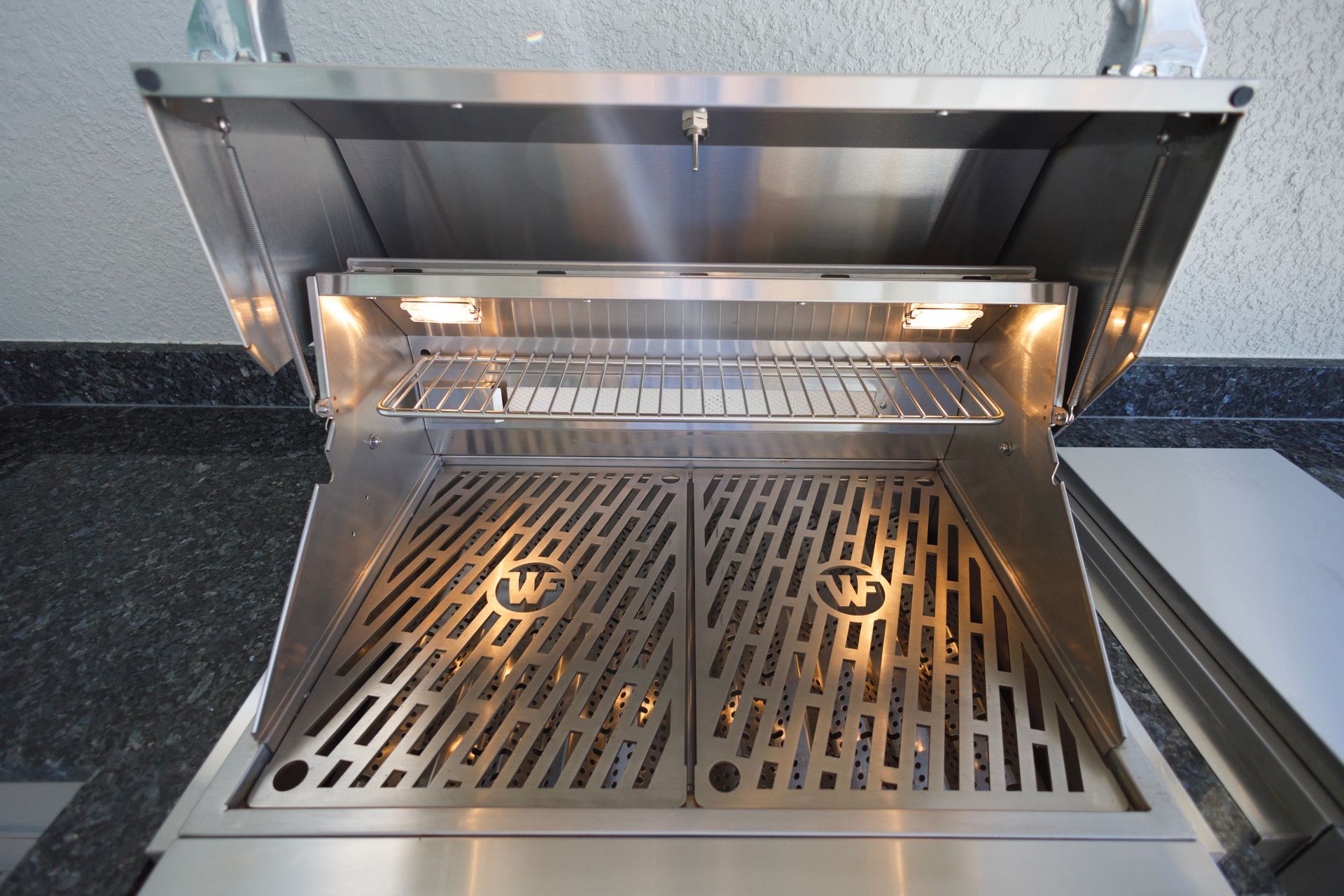 The inside of a stainless steel grill with the lid open