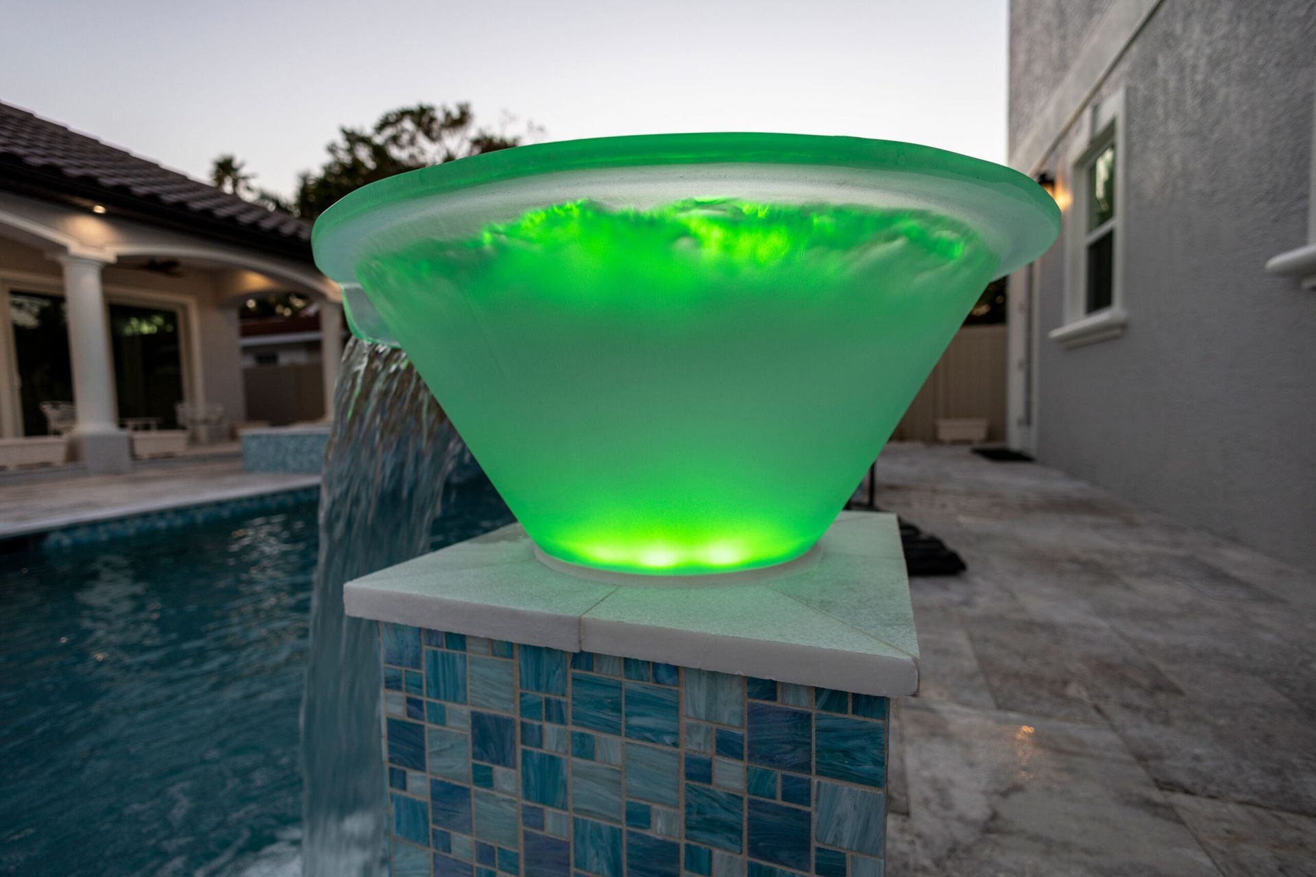 A green bowl is sitting next to a pool with a waterfall in the background.