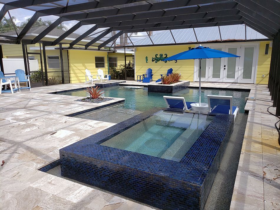 A large swimming pool with a blue umbrella and chairs.