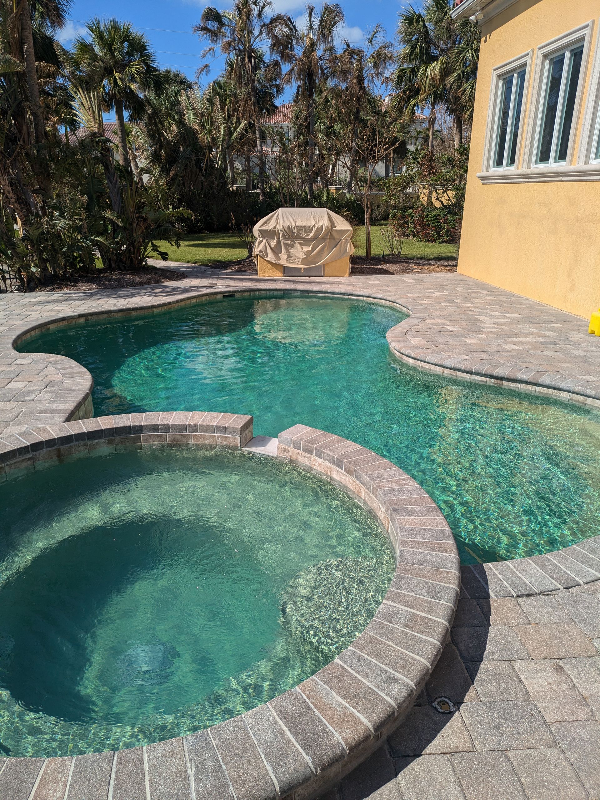 A large swimming pool with a hot tub in the middle of it.