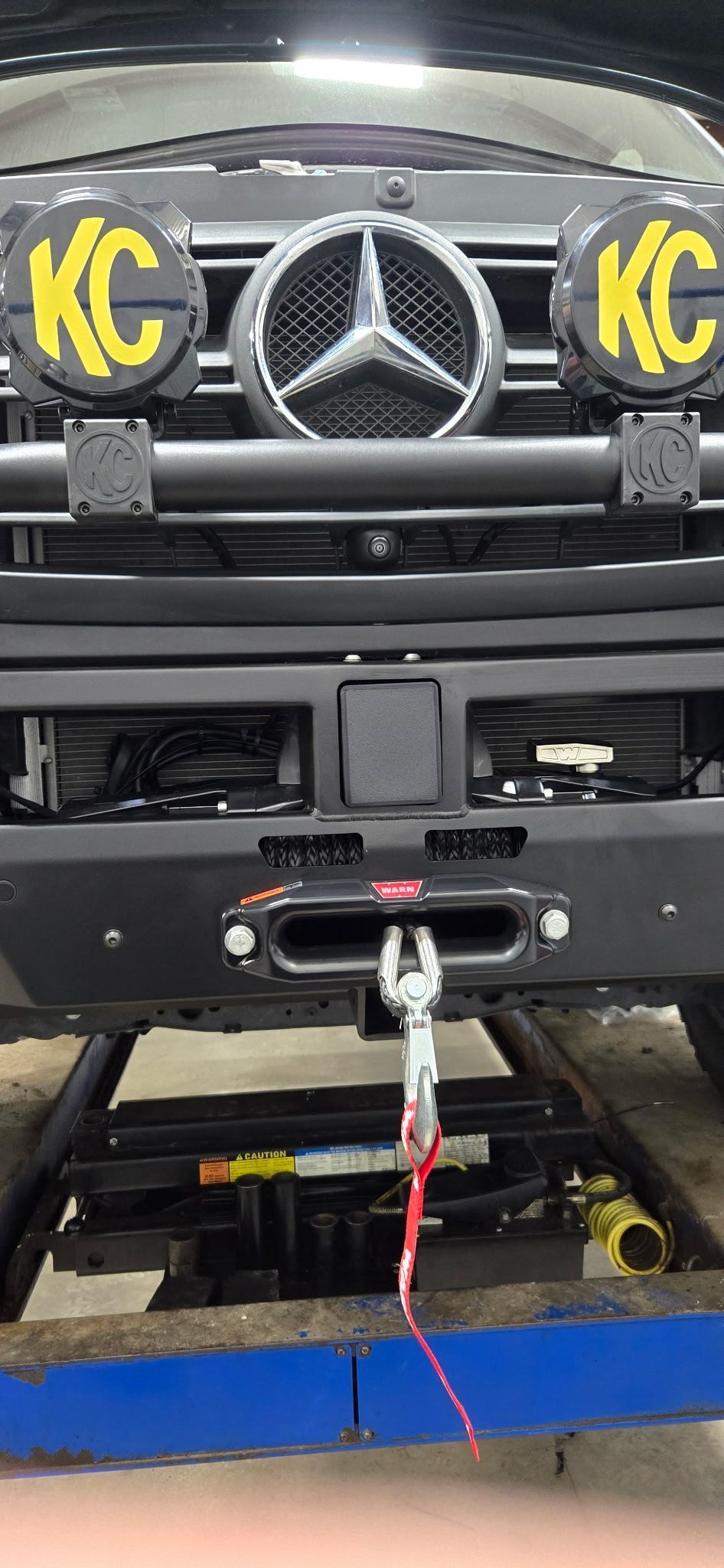 Black Mercedes-Benz with KC lights, winch, and red tow rope.