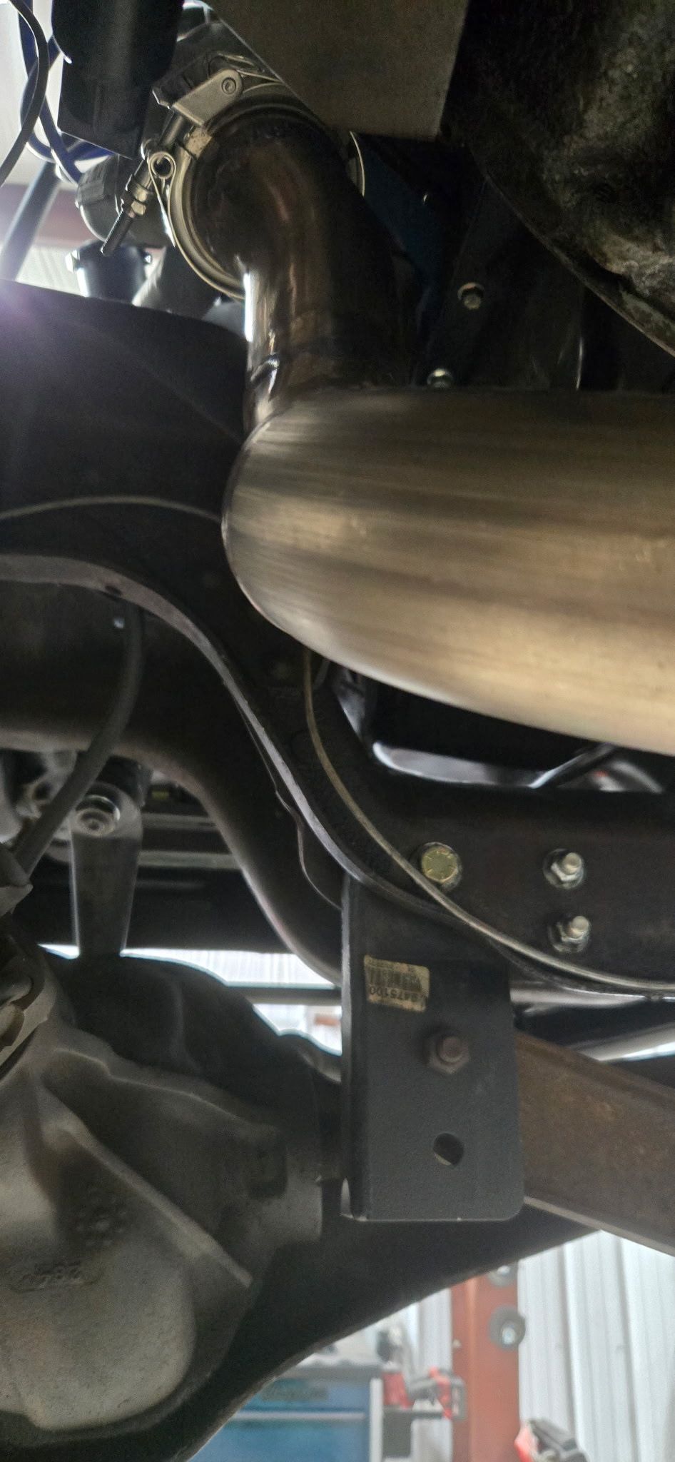 Undercarriage of a vehicle with exhaust pipe and suspension components.