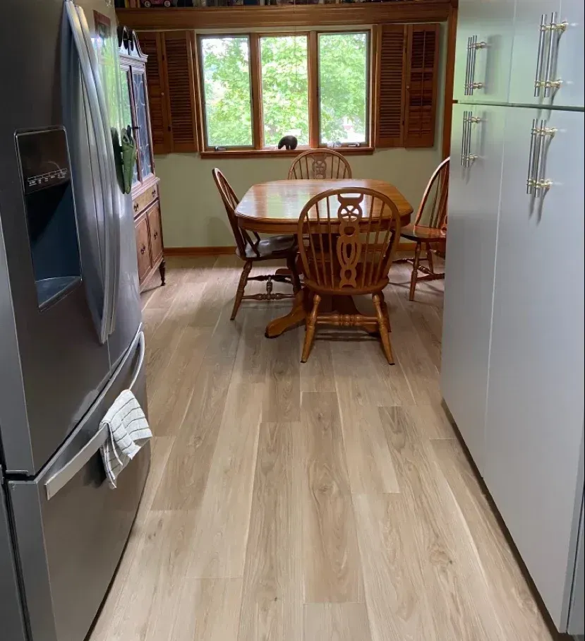 Small dining area with wooden table, chairs, and cabinet on a wooden floor - After