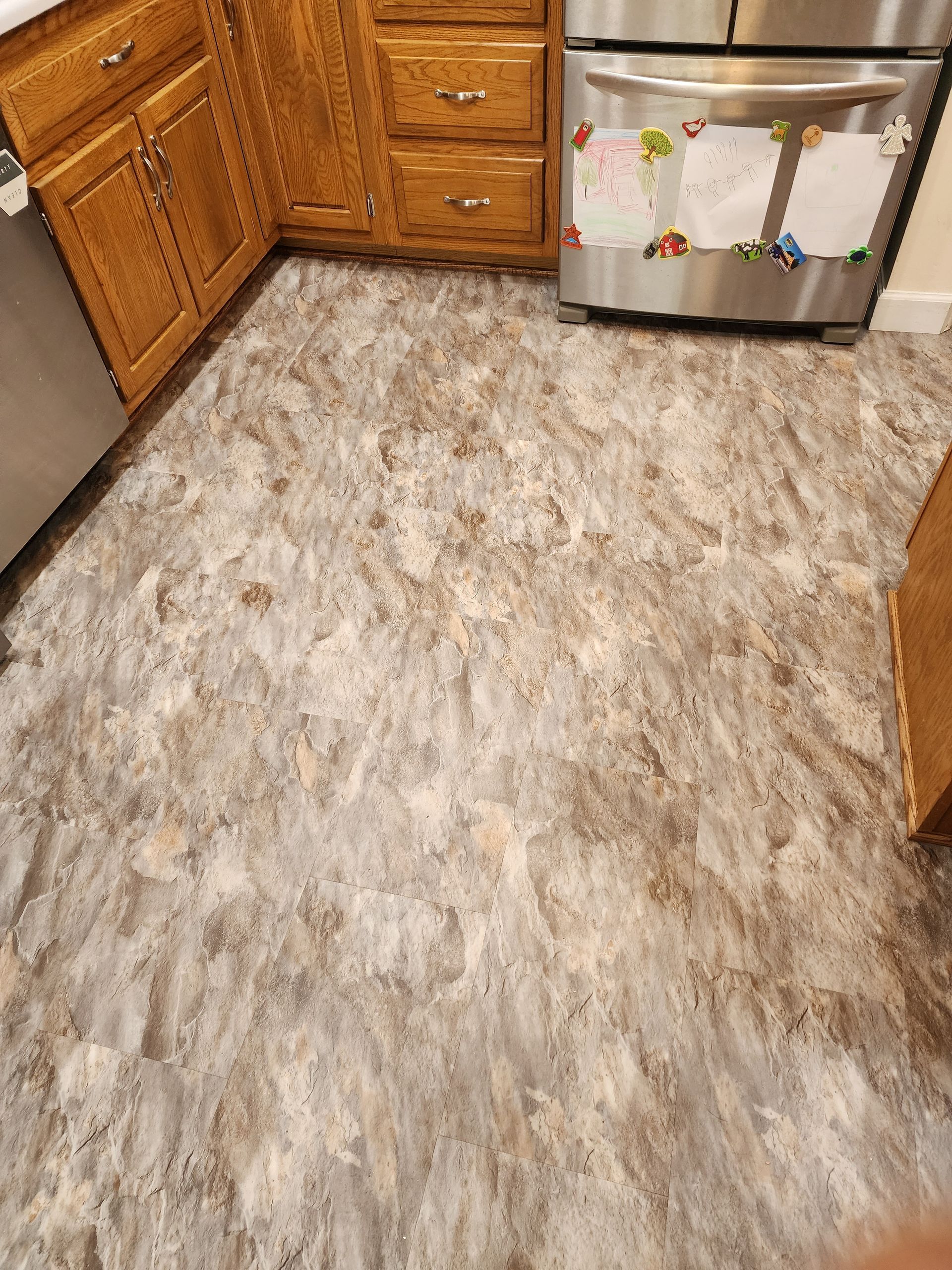 Kitchen with wood cabinets, stainless steel dishwasher, and a gray patterned floor tile.