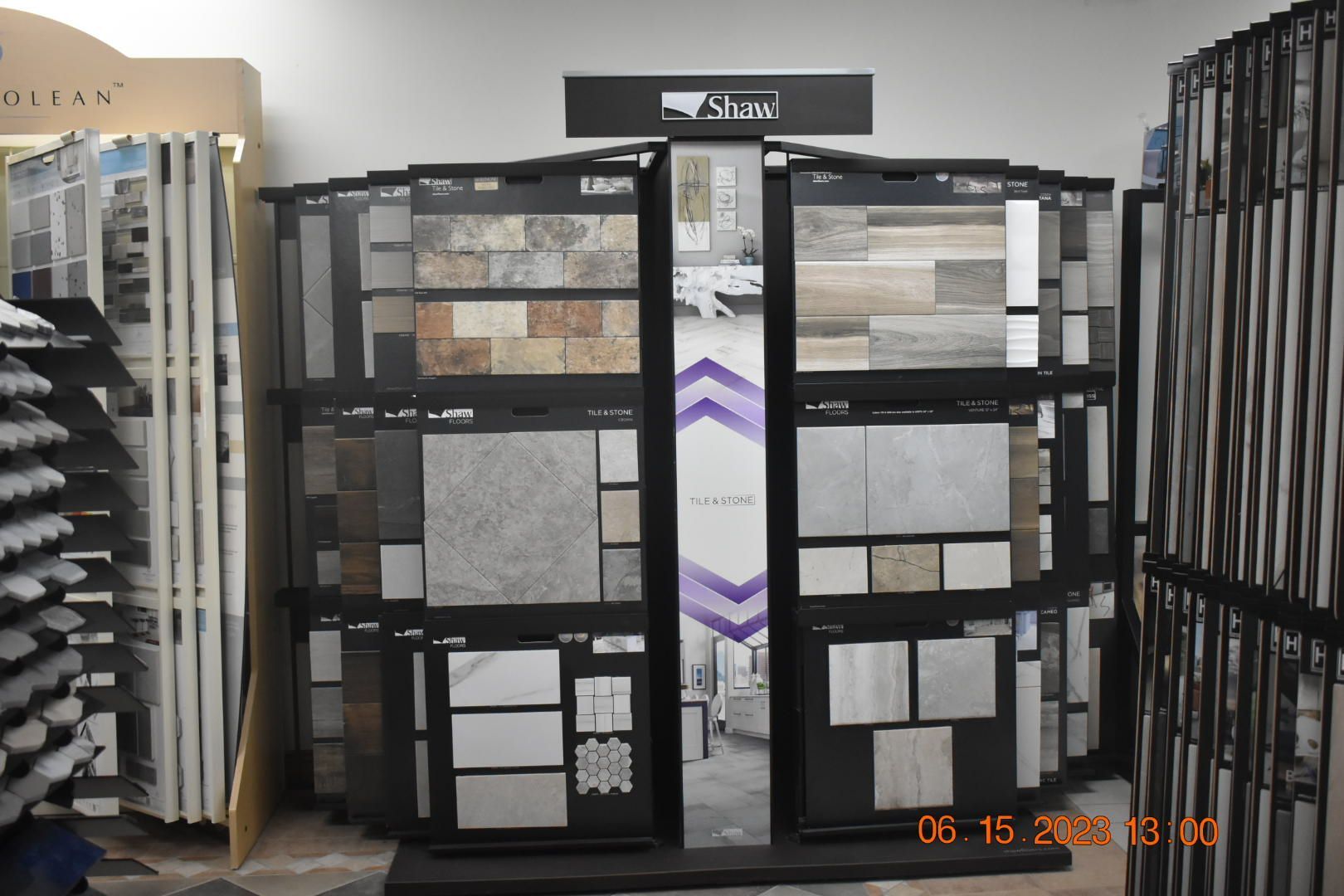 Tile showroom display racks with sample flooring and wall tiles in gray, white, and black tones