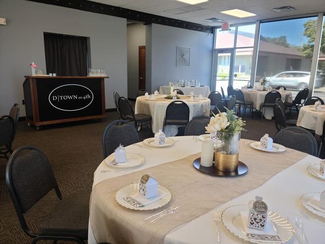 A banquet hall with round tables covered in white cloths, rustic burlap runners, and place settings with small favors.