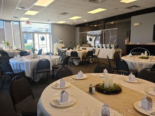 An event room with round tables covered in white tablecloths set for a gathering, featuring centerpieces and chairs.